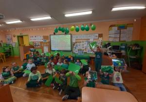 Dzieci machają zielonymi kartonikami w rytm piosenki